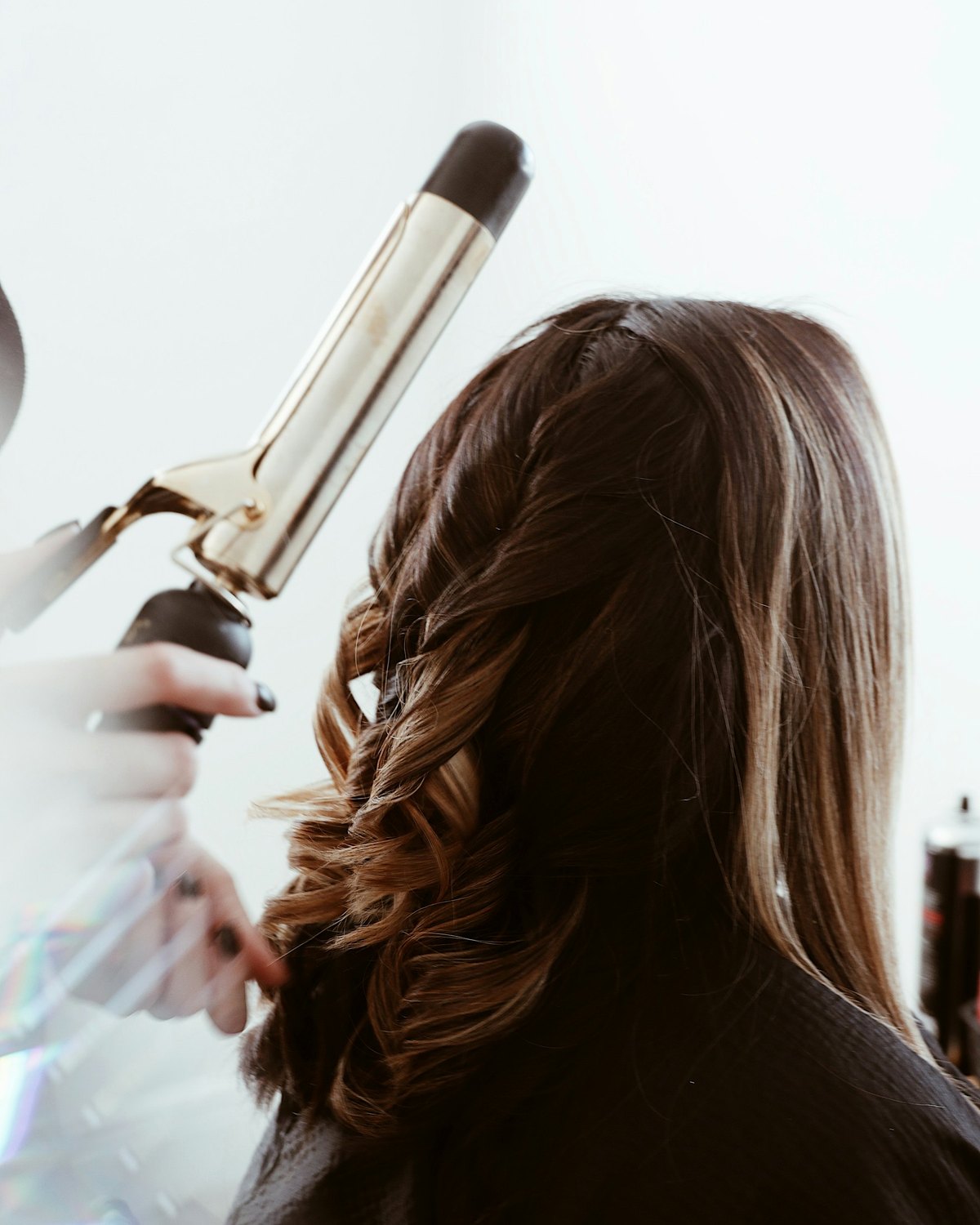 Mise en boucles au fer dans un salon de coiffure, vue de dos
